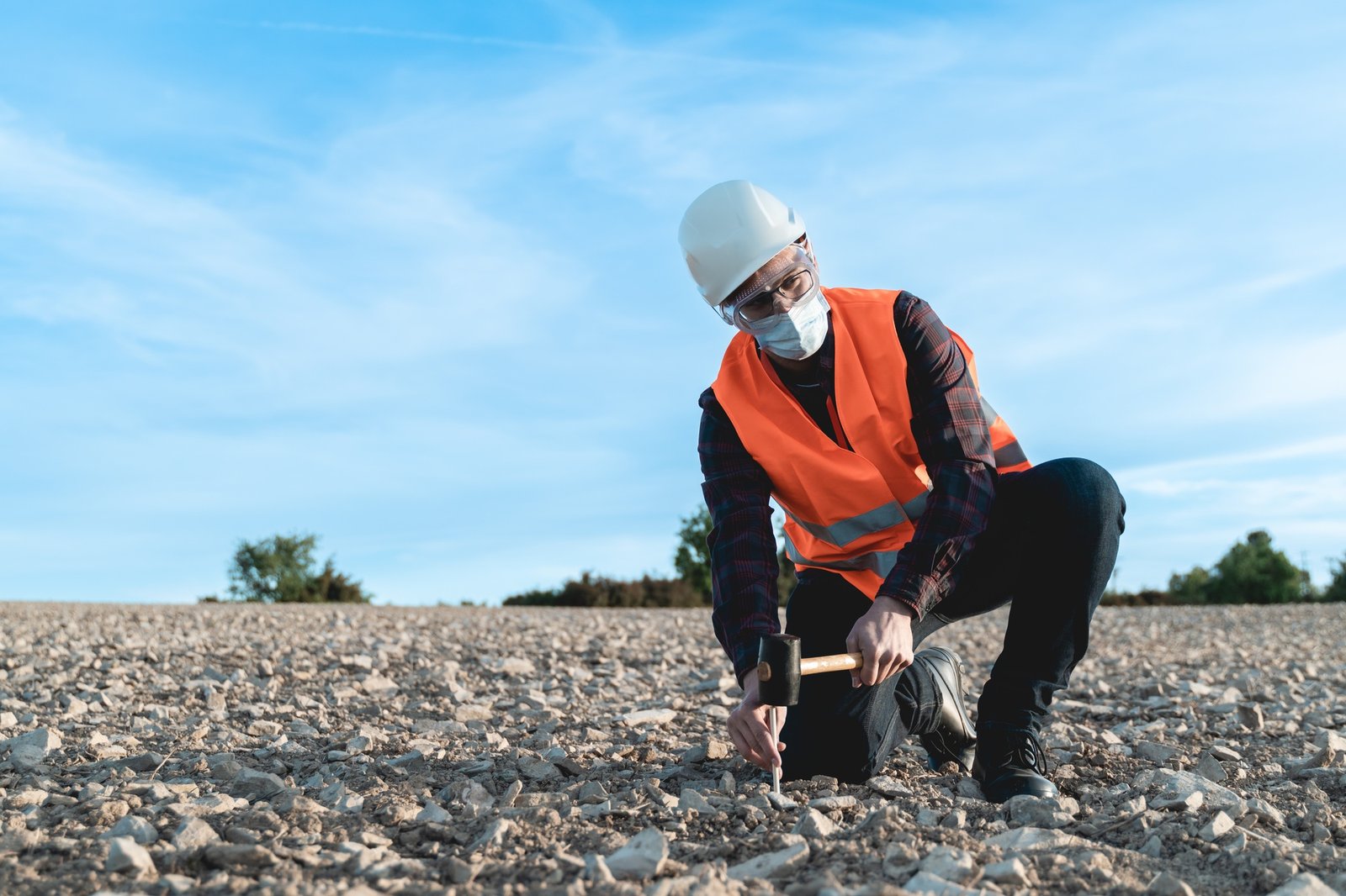 Engineer man doing topographic measures on land for construction work during coronavirus outbreak